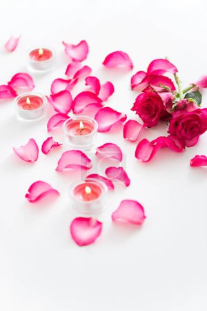 Téléchargez les photos : Belles bougies allumées avec des pétales de fleurs roses sur fond blanc - en image libre de droit