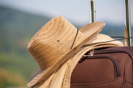 Foto de Maleta con sombrero de paja y chaqueta de pie al aire libre, concepto de viaje - Imagen libre de derechos
