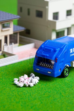 Foto de Camión de basura en miniatura recogiendo basura cerca de modelos de casa - Imagen libre de derechos