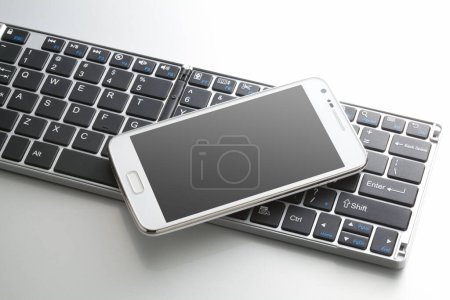 Photo for Close-up view of computer keyboard and mobile phone on white background - Royalty Free Image