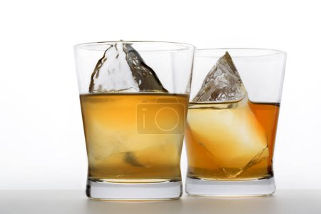 Foto de Vasos con bebidas alcohólicas y cubitos de hielo sobre fondo blanco - Imagen libre de derechos