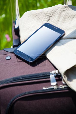Téléchargez les photos : Valise avec chapeau de paille et smartphone sur herbe verte, concept de voyage - en image libre de droit