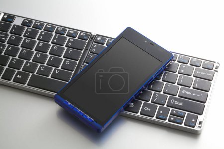 Foto de Vista de primer plano del teclado de la computadora y el teléfono móvil sobre fondo blanco - Imagen libre de derechos