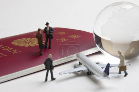 Foto de Figuras de personas en miniatura con avión de juguete, globo terráqueo de vidrio y pasaporte japonés - Imagen libre de derechos