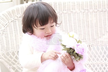 Téléchargez les photos : Mignonne asiatique petite fille portant écharpe rose tenant bouquet de roses à la maison - en image libre de droit