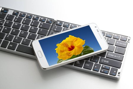 Photo for Close-up view of computer keyboard and mobile phone on white background - Royalty Free Image