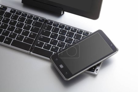 Foto de Vista de primer plano del teclado de la computadora y el teléfono móvil sobre fondo blanco - Imagen libre de derechos
