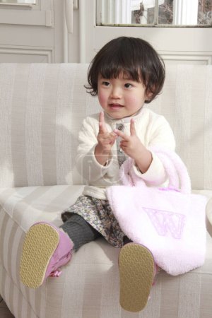 Téléchargez les photos : Mignonne asiatique petite fille tenant sac textile rose à la maison - en image libre de droit