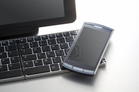 Téléchargez les photos : Vue rapprochée du clavier de l'ordinateur et du téléphone portable sur fond blanc - en image libre de droit