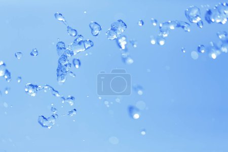 Foto de Salpicaduras de agua sobre fondo azul, de cerca - Imagen libre de derechos