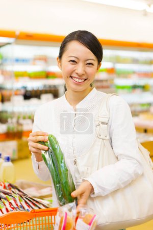 Téléchargez les photos : Souriant jeune femme japonaise dans l'épicerie - en image libre de droit
