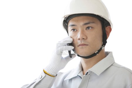 Téléchargez les photos : Travailleur de la construction japonais confiant avec smartphone. jeune homme avec casque sur fond blanc - en image libre de droit