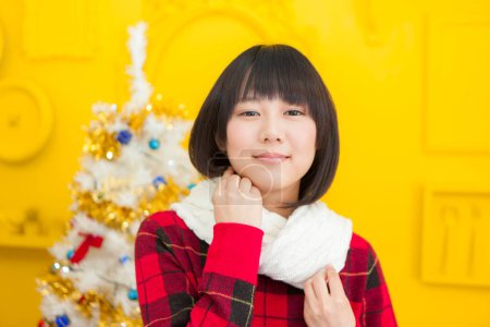Foto de Retrato de hermosa joven japonesa sobre fondo amarillo de la pared con árbol de Navidad - Imagen libre de derechos