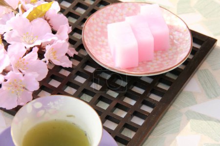 Téléchargez les photos : Cuisine photo de gelée de fruits roses, tasse de thé vert et fleurs de printemps - en image libre de droit