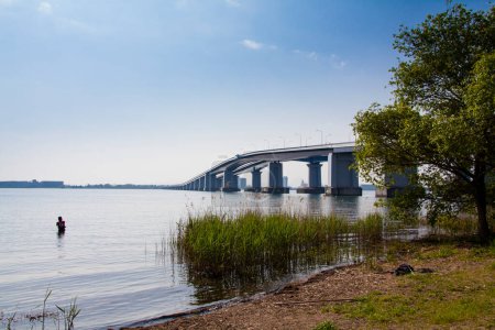 Téléchargez les photos : Homme pêche dans le lac près du pont - en image libre de droit