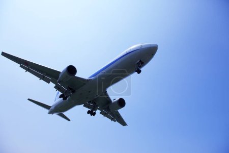 Photo for A large passenger jet flying through a blue sky - Royalty Free Image