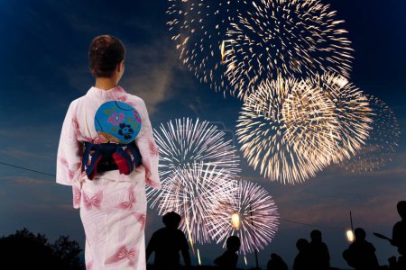 Photo for Young woman in traditional Japanese dress looking at fireworks celebrating new year - Royalty Free Image
