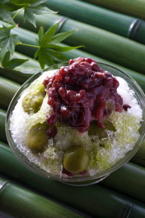 Photo for Cold shaved Matcha ice with Boiled azuki beans and plums on background, close up - Royalty Free Image