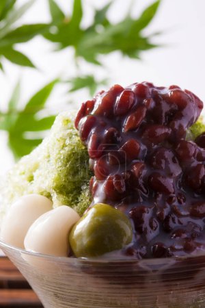 Téléchargez les photos : Glace Matcha rasée à froid avec haricots azuki bouillis et prunes sur fond, gros plan - en image libre de droit