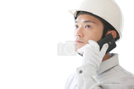travailleur de la construction japonais confiant avec smartphone. jeune homme avec casque sur fond blanc