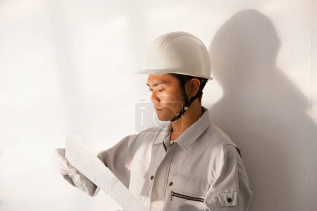 Téléchargez les photos : Portrait du beau jeune constructeur japonais en uniforme sur le chantier - en image libre de droit