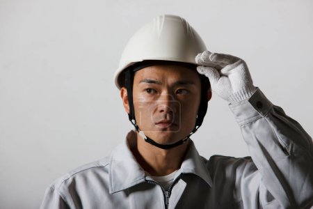 Foto de Retrato de joven constructor japonés guapo en uniforme en el sitio de construcción - Imagen libre de derechos