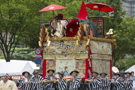 Téléchargez les photos : Festival Gion Matsuri. Des personnes portant un grand défilé de flotteurs traditionnels en bois dans la rue de la ville - en image libre de droit