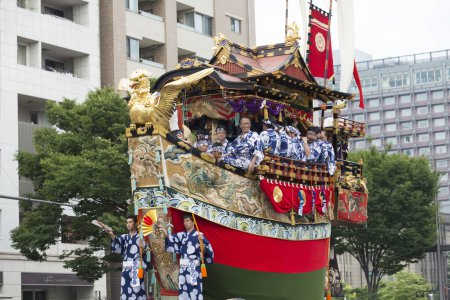 Téléchargez les photos : Festival Gion Matsuri, Procession Yamaboko Junko. Les gens tirant le grand défilé de flotteurs traditionnels en bois dans la rue de la ville - en image libre de droit