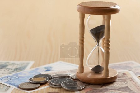 Photo for Hourglass and money on wooden table. Time is money, business concept - Royalty Free Image