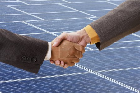 Foto de Dos hombres dándose la mano frente a un panel solar - Imagen libre de derechos