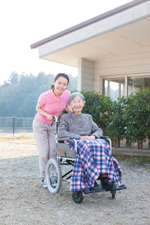 Photo for Asian female caregiver helping elderly asian woman on wheelchair - Royalty Free Image