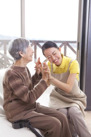 Téléchargez les photos : Femme heureuse Aide aidante femme asiatique plus âgée au canapé - en image libre de droit