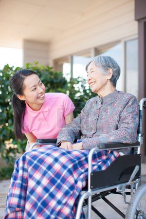 Photo for Asian female caregiver helping elderly asian woman on wheelchair - Royalty Free Image