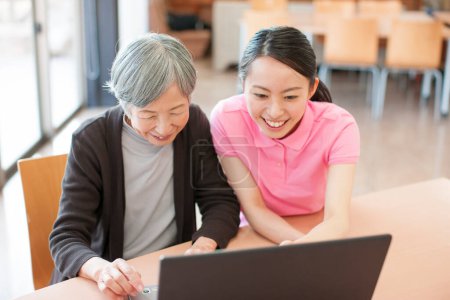 Photo for Young asian woman teaching elderly woman to use laptop at home - Royalty Free Image