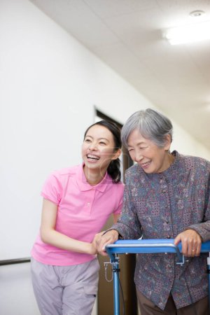 Foto de Mujer cuidador ayudar anciano asiático mujer en silla de ruedas - Imagen libre de derechos