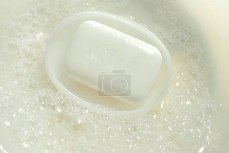 Foto de Jabón blanco en la caja de jabón sobre un fondo de espuma - Imagen libre de derechos