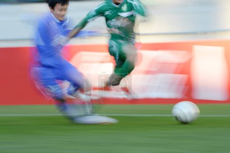 Téléchargez les photos : Jeunes Japonais jouant au football sur le stade, fond de sport avec des gens flous - en image libre de droit