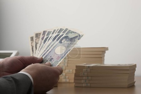 Téléchargez les photos : Les mains de l 'homme tenant de l' argent japonais, des billets en yen - en image libre de droit
