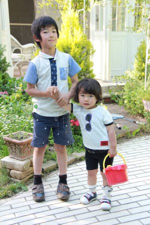 Téléchargez les photos : Asiatique garçon tenant la main de sa petite soeur dans le jardin - en image libre de droit