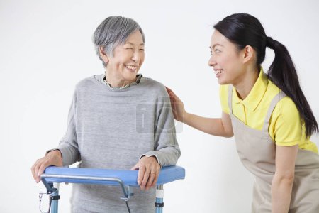 Photo for Asian Caregiver helping disabled older asian woman standing with walker - Royalty Free Image