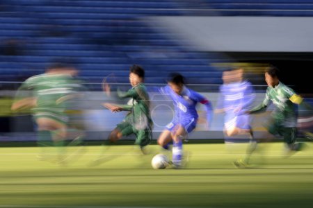 Téléchargez les photos : Jeunes Japonais jouant au football sur le stade, fond de sport avec des gens flous - en image libre de droit