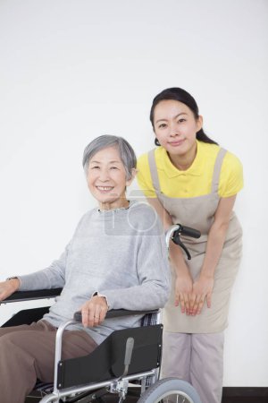 Foto de Asiático senior mujer en silla de ruedas y hembra asiático mujer - Imagen libre de derechos