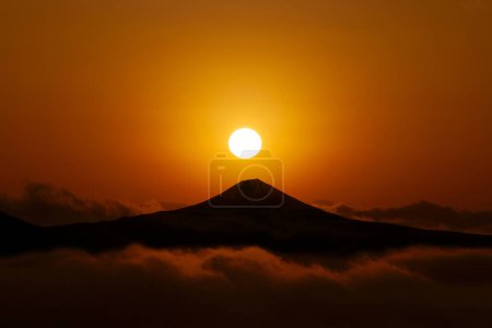 Foto de Una montaña con una puesta de sol detrás de ella - Imagen libre de derechos