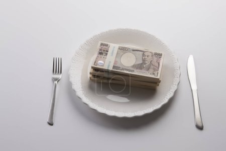 Téléchargez les photos : Une assiette de monnaie japonaise, billets de banque en yen avec fourchette et couteau - en image libre de droit