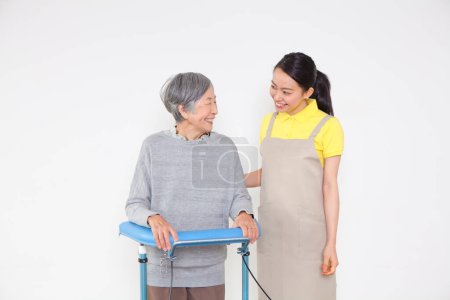 Téléchargez les photos : Souriant belle asiatique soignant et handicapé asiatique vieille dame avec marcheur - en image libre de droit