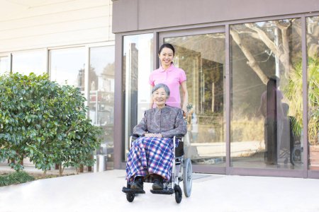 Téléchargez les photos : Femme asiatique aidante aidant femme âgée en fauteuil roulant - en image libre de droit