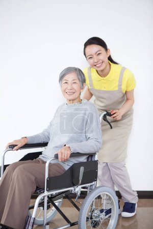 Téléchargez les photos : Jeune asiatique soignant aider les personnes âgées asiatique femme sur fauteuil roulant - en image libre de droit