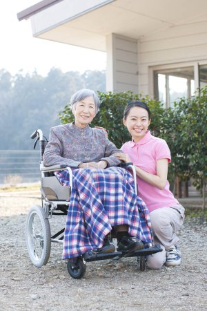 Téléchargez les photos : Femme asiatique aidante aidant femme âgée en fauteuil roulant - en image libre de droit