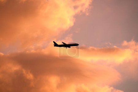 Téléchargez les photos : Silhouette d'avion volant avec un beau ciel couchant - en image libre de droit
