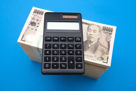 Foto de Calculadora con dinero del yen japonés sobre fondo azul. concepto de negocio - Imagen libre de derechos